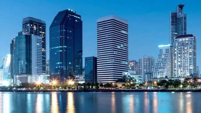 Prédios da cidade iluminados ao anoitecer, refletidos na água